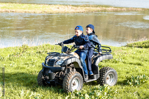 Friends are traveling by quad bike along the river bank.