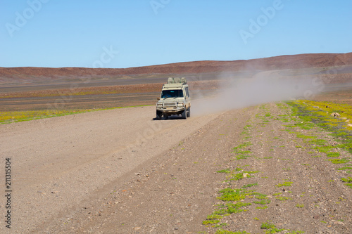 Dust trail follows safari vehicle along dusty road © Brian Scantlebury