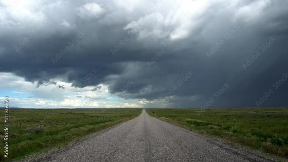 View looking down country road towards dramatic storm moving through the sky in the Idaho desert.