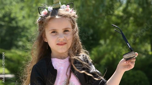 Little girl takes off sunglasses photo