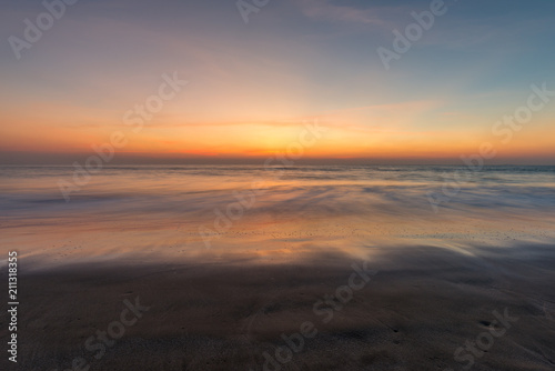Blurred waves on the beach, sunset cloudy sky.