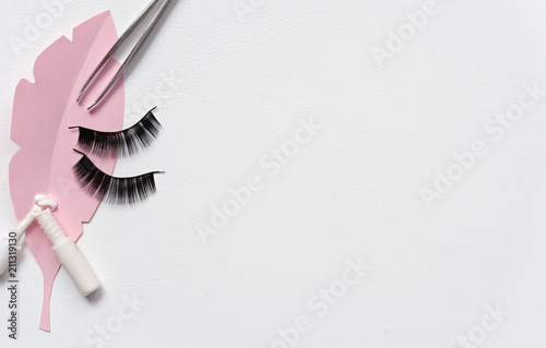 Black false lashes strips, tweezers, adhesive, on white background