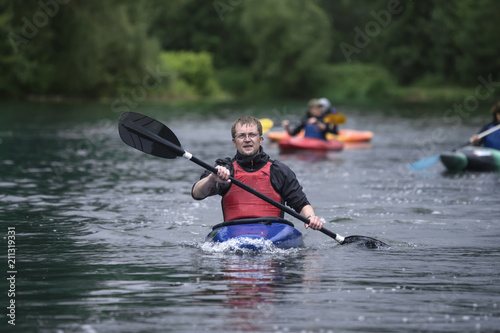 middle-aged man actively manages a sports boat with a kayak on a wide river.