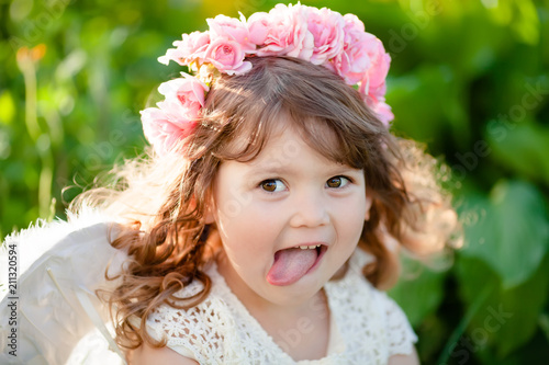 Cute little Angel girl with floral wreath, smiles and teases