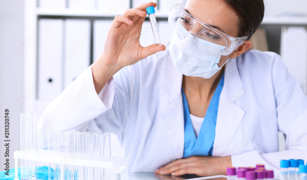 Female scientific research is looking at the tube in laboratory. Blood test concept Female scientific research is looking at the tube in laboratory. Blood test concept