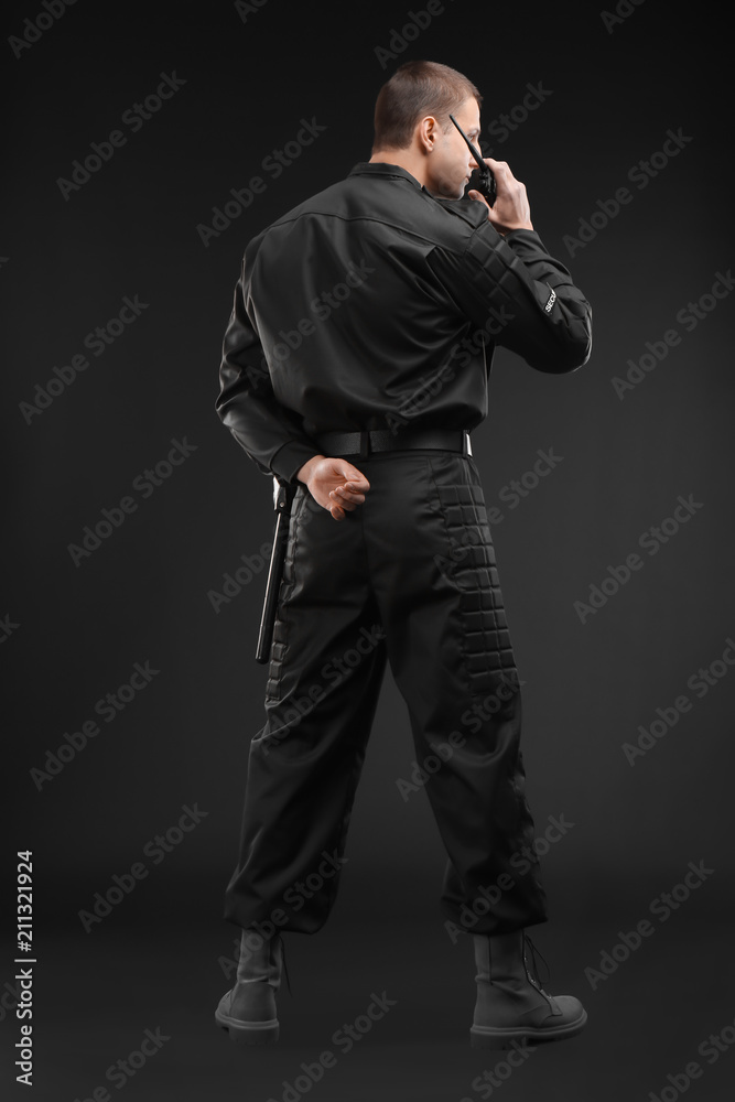 Male security guard using portable radio transmitter on dark background Male security guard using portable radio transmitter on dark background