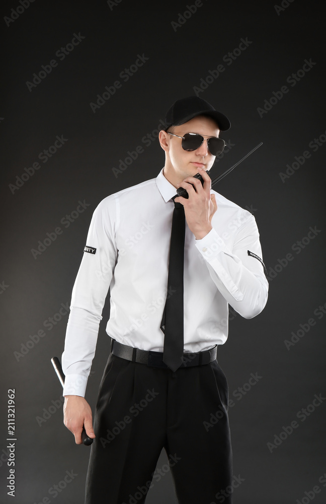 Obraz premium Male security guard using portable radio transmitter on dark background