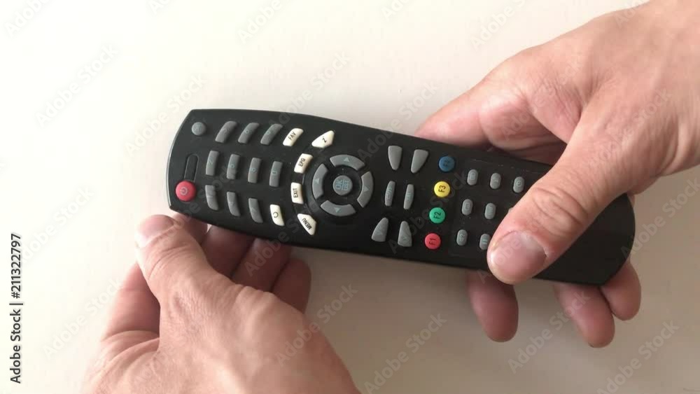 Hand holding tv remote and pushing power button. White background. Hand holding tv remote and pushing power button. White background.