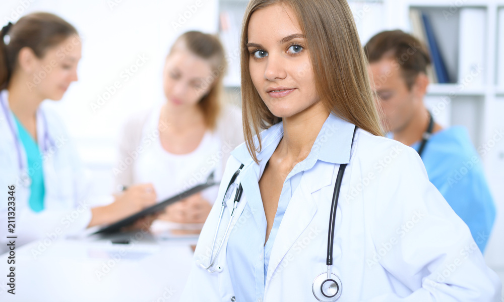 Happy doctor woman with medical staff at the background in hospital office Happy doctor woman with medical staff at the background in hospital office