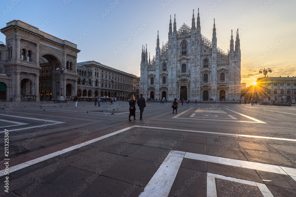 Tourists couple walking into the Duomo cathedral at sunrise, Milan. Italy 