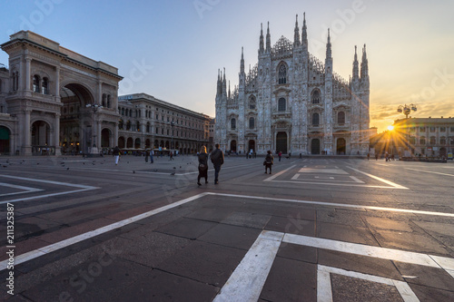 Tourists couple walking into the Duomo cathedral at sunrise, Milan. Italy 