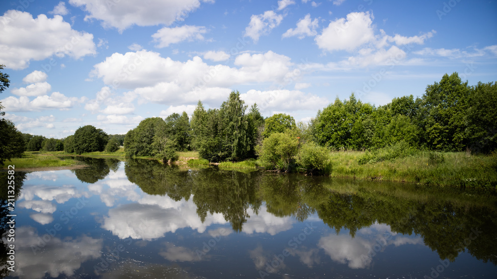 Calm lake water with clouds reflected. Sunny day.