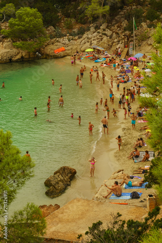 Benirras beach, Ibiza, Spain - 27 August, 2017: Young people jumping inside ocean in summer excursion day - Vacation, youth and fun concept - Soft focus on left man - Fisheye lens distortion photo