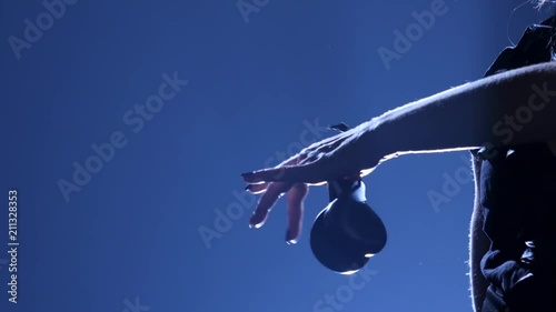 Girl is dancing in a hat with castanets in her hands dancing. Llight from behind. Dark background. Silhouette