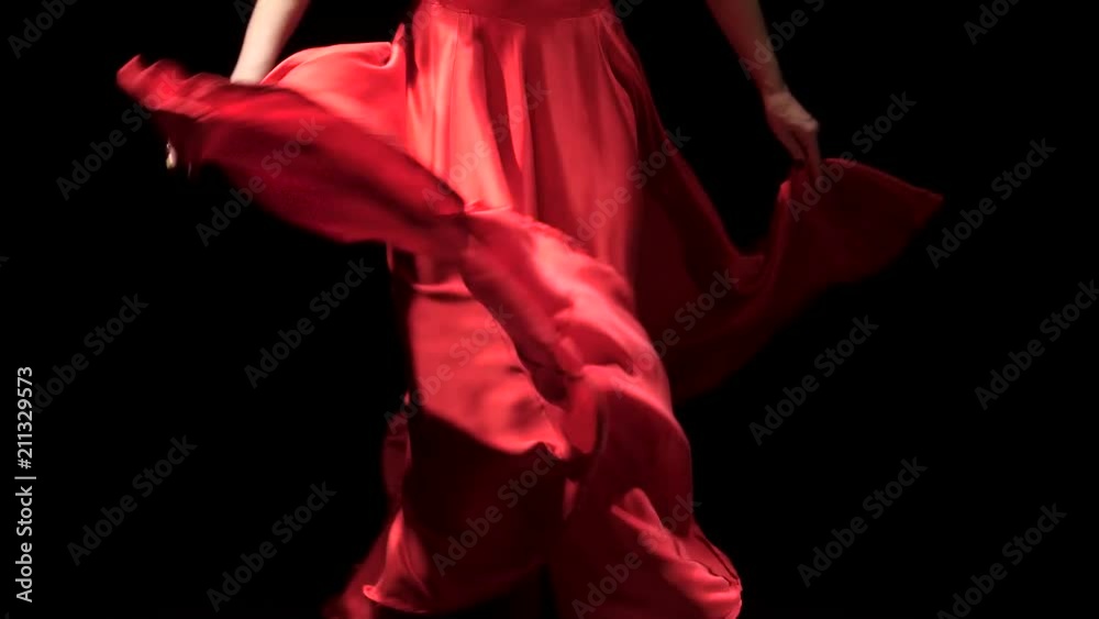 Woman in red dress performs elegant movements with her hands in dance. Black background. Close up