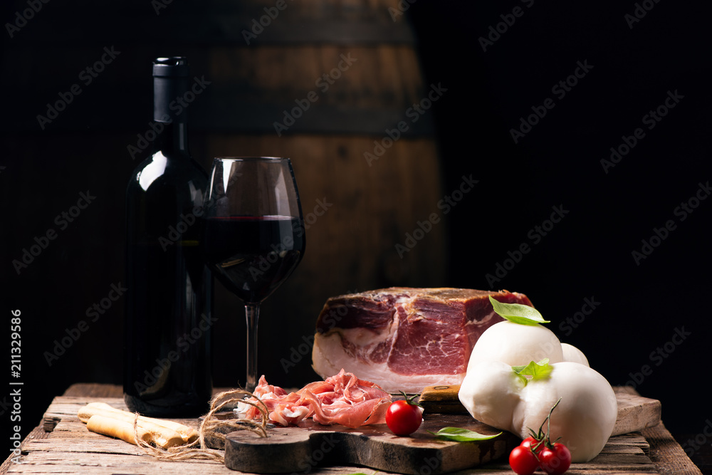 Bottle of wine with a glass on a table with rustic traditional italian food