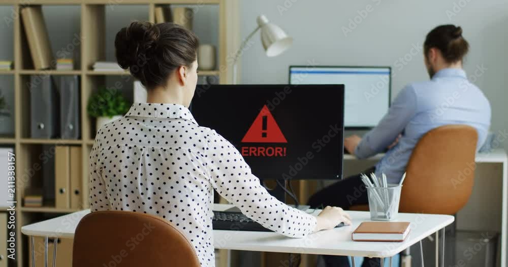 Rear of the brunette woman cannot work at the computer as there being error writing on its screen. At the office. Indoors.