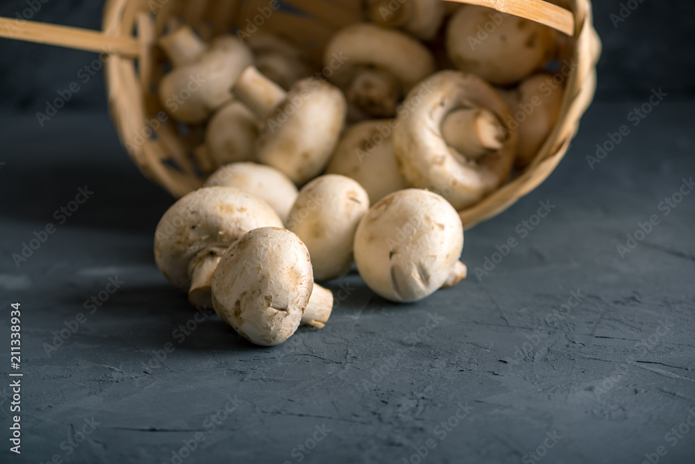 White Champions in the basket on the dark kitchen table. Cooking delicious dishes with mushrooms White Champions in the basket on the dark kitchen table. Cooking delicious dishes with mushrooms