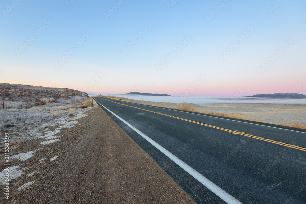 朝霧のかかったアメリカ大陸の真っ直ぐな一本道