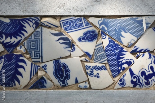 Canvas Print Broken blue and white china shards set in a wall