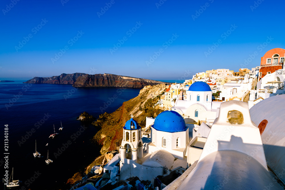Fototapeta premium Morning light shines across blue domes of Santorini island, Cyclades, Greece