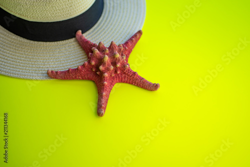 Red Starfish on summer straw hat, Bright Yellow surface, top view and close up. Free copy space. photo