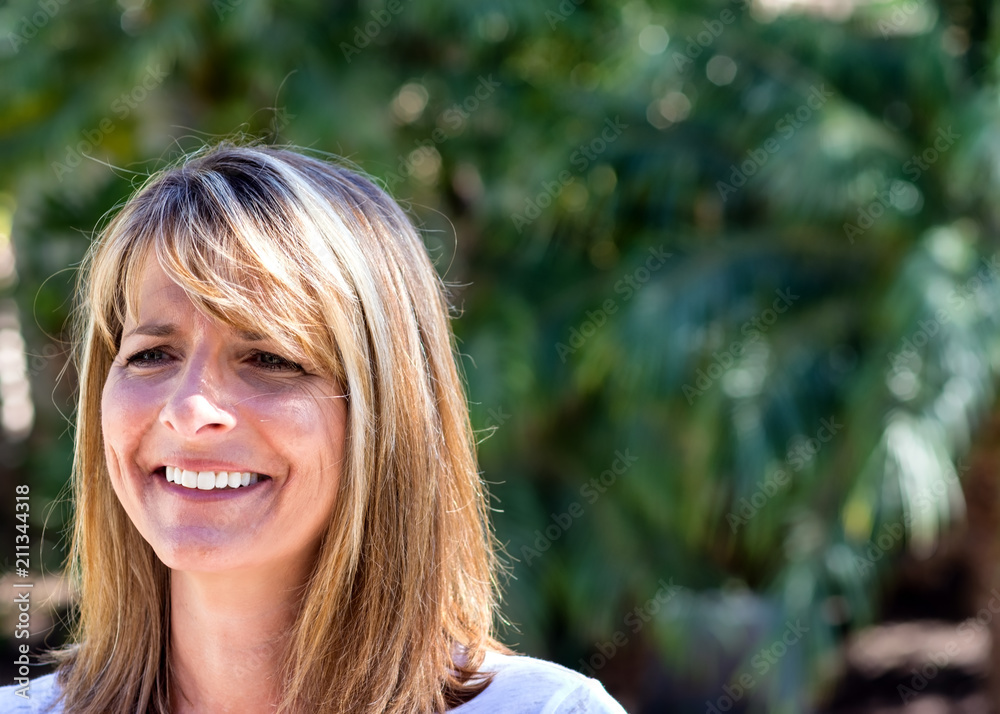 Very happy woman smiles during conversation outside in natural light
