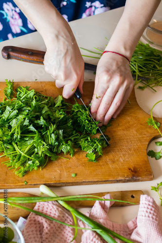 Woman hands cuts fresh herbs on wooden board preparing salad or lunch and dinner. Raw vegan vegetarian healthy food. 