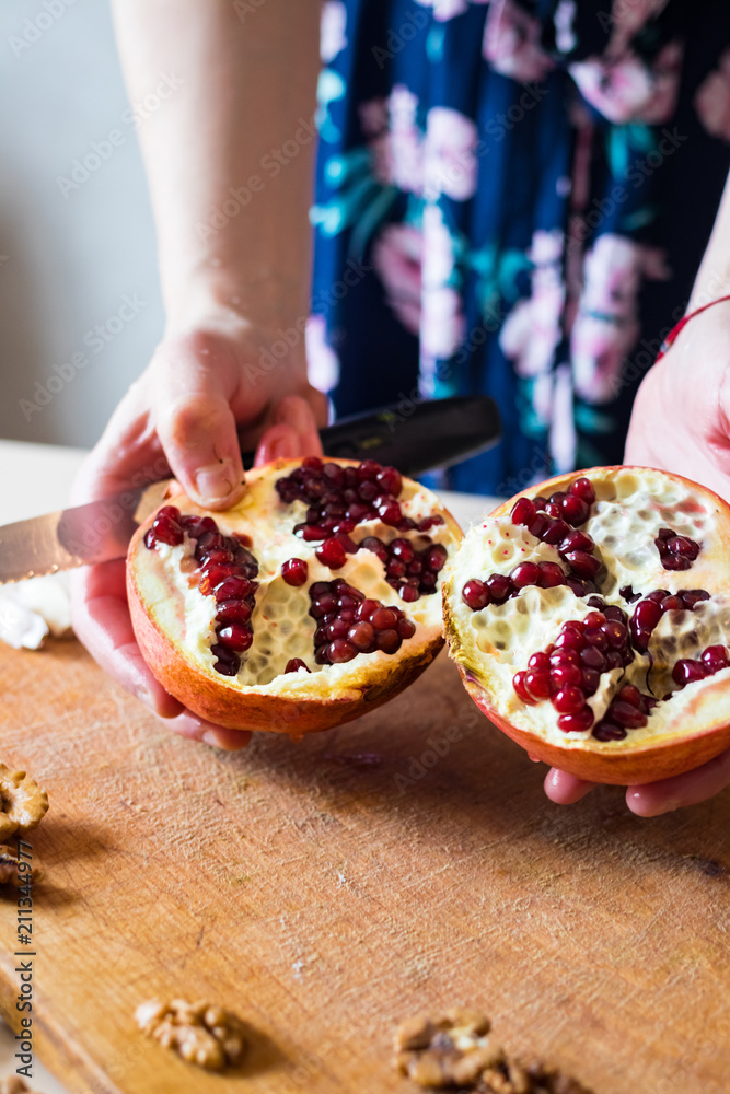 Woman hands peeling and carving pomegranate. Sweet asian fruit. Raw vegan vegetarian healthy food Woman hands peeling and carving pomegranate. Sweet asian fruit. Raw vegan vegetarian healthy food