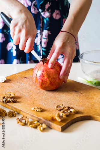 Woman hands peeling and carving pomegranate. Sweet asian fruit. Raw vegan vegetarian healthy food