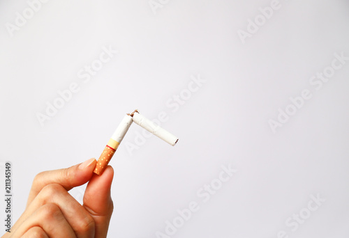 Broken cigarette in woman's hand, symbol of stop smoking.