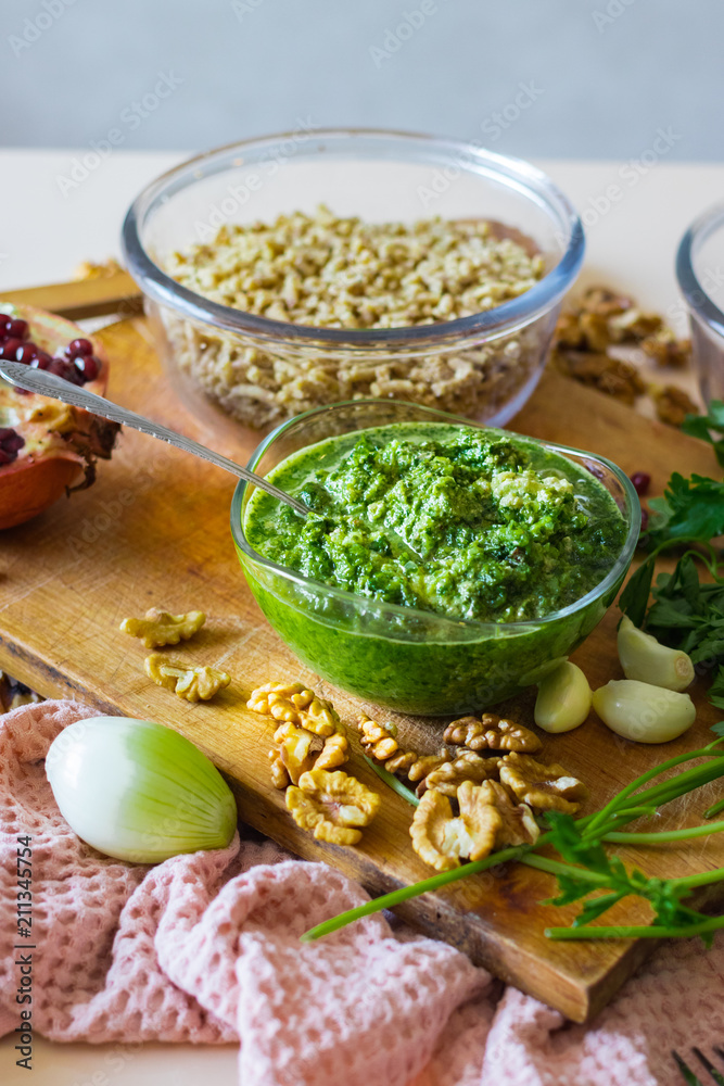Pkhali ingredients: cilantro mixed with onion, garlic and green adjika, pomegranate, walnuts. Traditional Georgian food appetizer. Preparation process. Pkhali ingredients: cilantro mixed with onion, garlic and green adjika, pomegranate, walnuts. Traditional Georgian food appetizer. Preparation process.