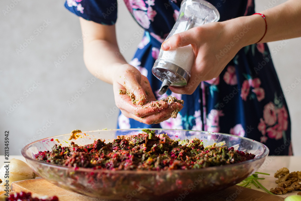 Woman hands adds salt and preparing ingredients for pkhali balls - traditional Georgian food with walnuts beetroot and spinach.