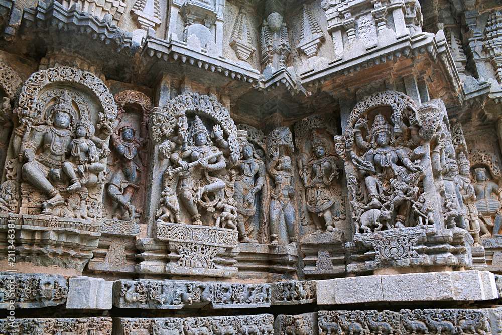 Ornate wall panel reliefs depicting from left Shiva-Parvati, dancing Sarswati, and Mahishsuramardini on the extere right, Kedareshwara temple, Halebidu, Karnataka