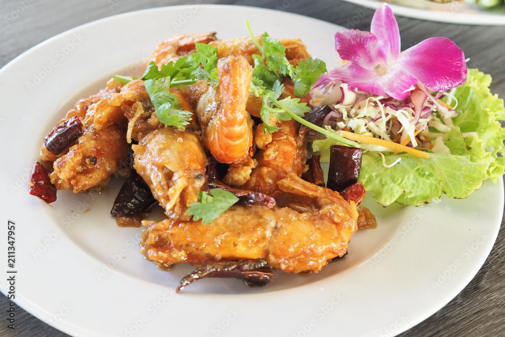 Fried shrimps with tamarins and fried dried chili sour and sweet sauce decorate with vegetables on white ceramic dish ready for serve Fried shrimps with tamarins and fried dried chili sour and sweet sauce decorate with vegetables on white ceramic dish ready for serve