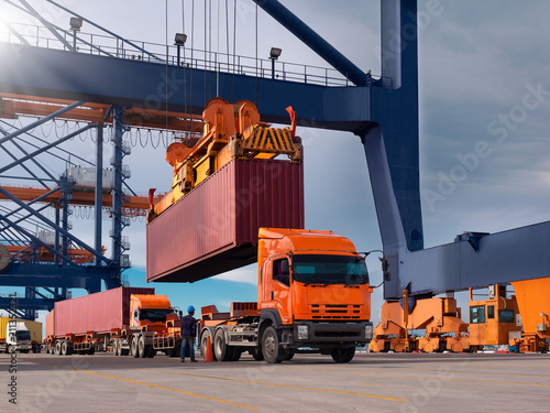 The container vessel during loading at an industrial port by port crane.