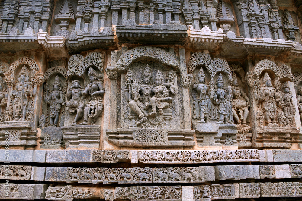 Ornate wall panel reliefs depicting Shiva-Parvati in the centre, and other deities, North wall, Kedareshwara temple, Halebidu, Karnataka