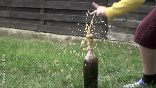 A little boy doing an experiment with soda in which there's an eruption  of the liquid from the top of the bottle. photo