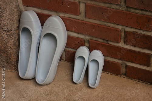 The rubber shoes are standing on the brick wall 