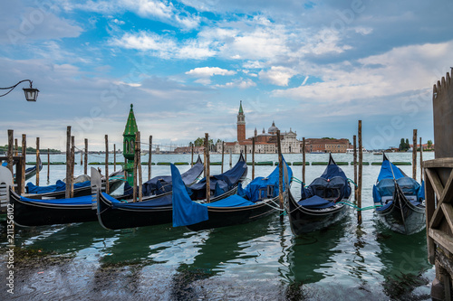 Gondolas moored by Saint Mark square with San Giorgio di Maggiore church on blurry background in Venice, Italy
