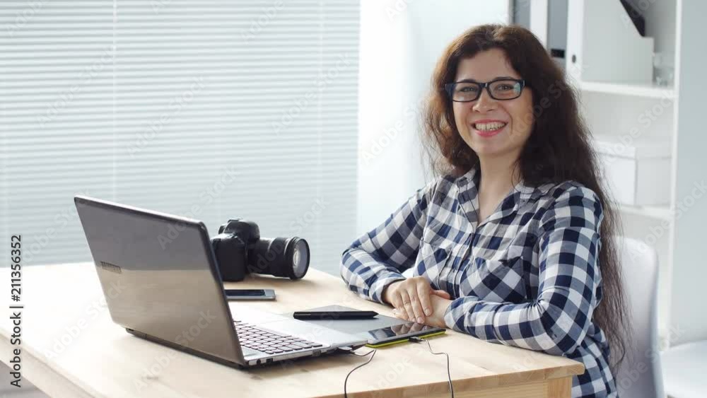 Smiling woman designer working on computer in office Smiling woman designer working on computer in office