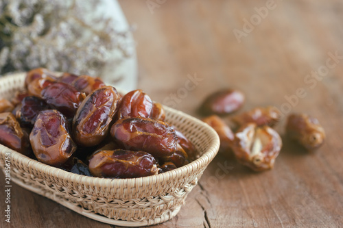 Khalas date palm on wooden basket in side view with copy space on wood table for background. Dates fruit is food for Ramadan or medjool. Delicious dried fruit with sweet taste and have high fiber. photo