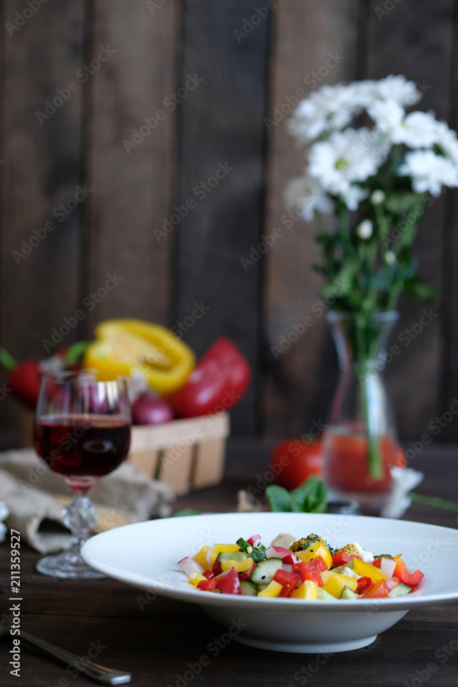 flowers, vine and serving of salad from vegetables on old wooden table