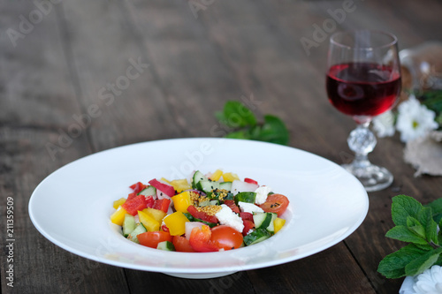 flowers, wine and serving of salad from vegetables on old wooden table