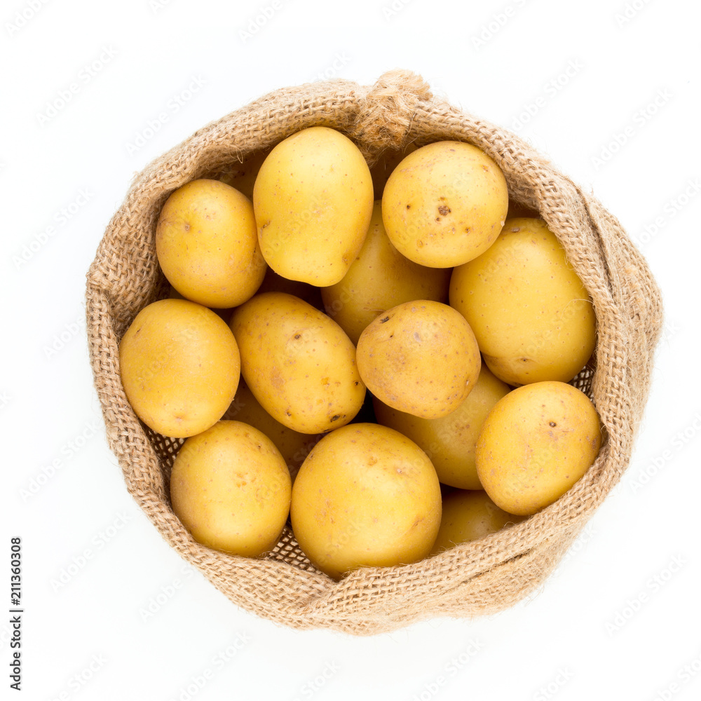 Sack of fresh raw potatoes on wooden background, top view