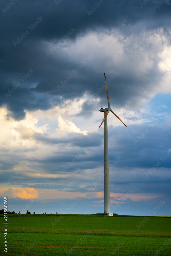 Dramatic sky over wind turbine on green field