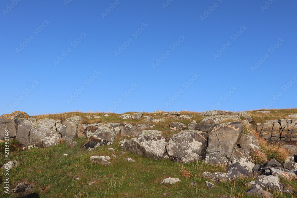 Rocks at top of cliff with blue sky and copy space