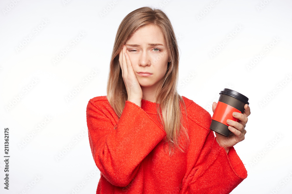Sleepy attractive female student worked all day at diploma paper, poses indoors with cup of coffee, wants to have rest, being tired and exhausted. Exhausted woman in red sweater is tired from work. Sleepy attractive female student worked all day at diploma paper, poses indoors with cup of coffee, wants to have rest, being tired and exhausted. Exhausted woman in red sweater is tired from work.