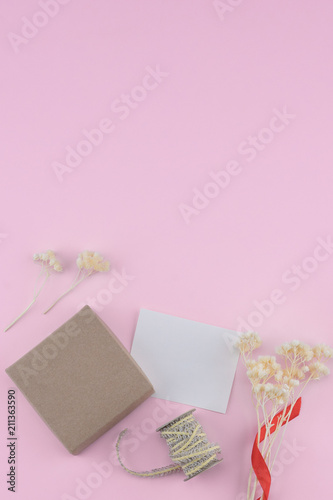 Blank white card, brown gift box and rope decorate with white dried flowers bouquet on pastel pink background with copy space © nathiyai