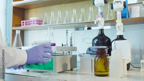 Top view. Chemical analysis laboratory. Close up hands of the scientist putting the funnel in the flask standing on the heating device